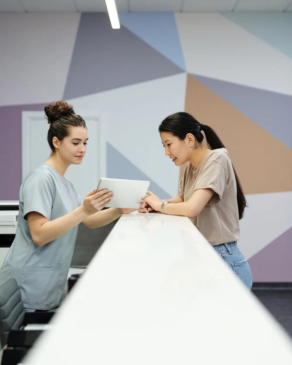Receptionist showing the schedule on a tablet to a patient at the front desk